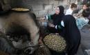نساء فلسطينيات يُجهّزن ويخبزن كعكات العيد التقليدية على أفران مؤقتة داخل مأوى قرب منطقة “الخط الأصفر” شرق مدينة غزة، قبيل عيد الأضحى، 25 مايو/أيار 2026. تصوير: بلال أسامة