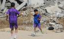 أطفال فلسطينيون نازحون يرتدون الزي الرياضي يشاركون في حصة تدريبية لكرة القدم مع مدربهم في ساحة صغيرة وسط أنقاض المنازل المدمرة في حي الشيخ رضوان بمدينة غزة، 16 حزيران/يونيو 2026. تصوير: بلال أسامة