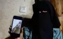رنا أبو نصار والدة الأسير أسامة أبو نصار المحتجز لدى إسرائيل تحمل هاتفاً محمولاً يعرض صورة انتشرت على نطاق واسع، تعتقد أنها تُظهر ابنها مقيداً، مخيم المغازي وسط قطاع غزة (رويترز).webp