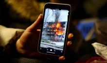 امرأة تنظر إلى صورة لحريق شقة صديقتها على هاتفها، أثناء انتظارها ركوب القطار إلى كراكوف بعد عبور الحدود من أوكرانيا إلى بولندا. 09/03/2022. (فابريزيو بينش/ رويترز)