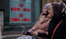 سيدات يسيرون أمام لوحة تعرض أسعار صرف عملات الدولار الأميركي واليورو مقابل الروبل الروسي في موسكو. 22/02/2022. (أ ف ب)