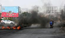 متظاهرون يحملون الأعلام الفلسطينية ويحرقون الإطارات على حاجز حوارة احتجاجا على استمرار الحصار الإسرائيلي على مدينة نابلس