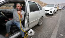 سائق سيارة فلسطيني يدخن النرجيلة وهو داخل مركبته في انتظار عبور حاجز تفتيش إسرائيلي بين مدينة نابلس الفلسطينية وقرية بيت فوريك في الضفة الغربية 6.jpg
