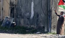 فلسطيني يلوّح بالعلم الوطني خلال مواجهات مع قوات الاحتلال الإسرائيلي في قرية كفر قدوم، 17 شباط/فبراير 2023. (أ ف ب)