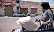 امرأة تنظر إلى سيارات محترقة في اللد، بهبة الكرامة (Getty Images)