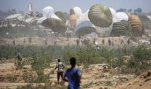 فلسطينيون يهرعون إلى موقع إسقاط مساعدات جواً في النصيرات وسط قطاع غزة يوم الأربعاء.jpeg