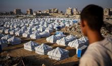 نازحون فلسطينيون يسيرون وسط ملاجئ مؤقتة شمال مدينة غزة