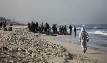 صيادون فلسطينيون نازحون يجمعون صيدهم من الشباك التي جلبوها إلى الشاطئ في دير البلح، في وسط قطا (3).jpg