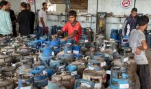 عمال يتعاملون مع أسطوانات الغاز في محطة تعبئة في النصيرات، وسط قطاع غزة، في وقت يعاني فيه القطاع من أزمة حادة في إمدادات الوقود.تصوير: بلال أبو عامر