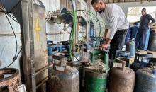 عمال يتعاملون مع أسطوانات الغاز في محطة تعبئة في النصيرات، وسط قطاع غزة، في وقت يعاني فيه القطاع من أزمة حادة في إمدادات الوقود.تصوير: بلال أبو عامر