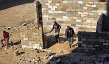 في خان يونس، جنوب قطاع غزة، يقوم أصحاب المتاجر الفلسطينيون بإزالة الأنقاض بأيديهم، ويعيدون بناء متاجرهم المتضررة باستخدام الحجارة والطين الأحمر، 27 ديسمبر/كانون الأول 2025 (صورة: طارق محمد)