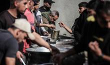 يتلقى فلسطينيون في مخيم النصيرات وسط قطاع غزة وجبات ساخنة من جمعية خيرية تُعنى بالنازحين جراء الهجمات الإسرائيلية، بينما يتجمع حشد كبير، يضم نساءً وأطفالاً، خلال عملية التوزيع، في 30 ديسمبر/كانون الأول 2025. صورة: معز صالحي