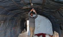 الفلسطيني هشام أبو عية يبني مأوى مؤقت لعائلته المكونة من ثمانية أفراد باستخدام قضبان حديدية استخرجها من أنقاض منزله الذي دُمر في هجمات إسرائيلية بمنطقة بطن السمين في خان يونس،  19 ديسمبر/كانون الأول 2025. تصوير: طارق محمد/ (APA )