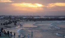 يقضي فلسطينيون نازحون وقتًا على الشاطئ مقابل خيامهم الممتدة على طول ميناء غزة، في غزة، 5 ديسمبر/كانون الأول 2025. تصوير: عمر أشتوي