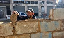 في خان يونس، جنوب قطاع غزة، يقوم أصحاب المتاجر الفلسطينيون بإزالة الأنقاض بأيديهم، ويعيدون بناء متاجرهم المتضررة باستخدام الحجارة والطين الأحمر، 27 ديسمبر/كانون الأول 2025 (صورة: طارق محمد)