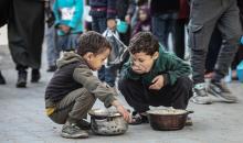 يتلقى فلسطينيون في مخيم النصيرات وسط قطاع غزة وجبات ساخنة من جمعية خيرية تُعنى بالنازحين جراء الهجمات الإسرائيلية، بينما يتجمع حشد كبير، يضم نساءً وأطفالاً، خلال عملية التوزيع، في 30 ديسمبر/كانون الأول 2025. صورة: معز صالحي