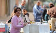 يتجمع الفلسطينيون لتلقي مياه الشرب مجانًا في مخيم البريج للاجئين، في ظل تفاقم أزمة نقص المياه وتدهور البنية التحتية، 21 ديسمبر/كانون الأول 2025. صورة: رمزي أبو عامر