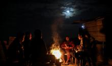 يعيش الفلسطينيون حياتهم اليومية ليلاً في خيام نصبت فوق أنقاض المباني المدمرة في حي الشيخ رضوان وسط مدينة غزة، 5 ديسمبر/كانون الأول 2025.تصوير: عمر أشتوي