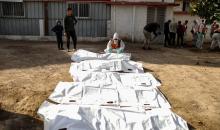 منقذون ومتطوعون فلسطينيون يستخرجون جثث ضحايا الحرب من مقبرة مؤقتة داخل المستشفى العربي المعمداني بمدينة غزة، ليعاد دفنها