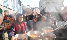 يتلقى الفلسطينيون، بمن فيهم الأطفال، الذين يعانون من صعوبة الحصول على الغذاء بسبب الهجمات الإسرائيلية المستمرة، وجبات ساخنة توزعها إحدى الجمعيات الخيرية في مخيم النصيرات للاجئين وسط قطاع غزة، 5 يناير/كانون الثاني 2026. تصوير: أحمد إبراهيم