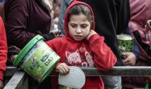 أطفال فلسطينيون ينتظرون وجبة ساخنة، توزعها إحدى المنظمات الخيرية، في ظل استمرار أزمة الغذاء بسبب محدودية المساعدات الإنسانية في مخيم النصيرات للاجئين وسط قطاع غزة، في 10 يناير/كانون الثاني 2026. صورة: معز صالحي