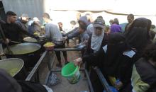 يتجمع فلسطينيون لتناول وجبة ساخنة وزعتها إحدى الجمعيات الخيرية، وسط أزمة غذائية مستمرة بسبب محدودية المساعدات الإنسانية خلال شهر رمضان في مخيم النصيرات للاجئين وسط قطاع غزة. ٢٣ فبرايرشباط ٢٠٢٦. تصوير معز صالحي