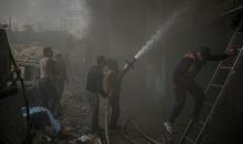 طواقم الدفاع المدني ومتطوعون من المواطنين أثناء محاولة إخماد حريق اندلع في مستودع تابع لمنظمة إغاثة في حي الرمال، غرب مدينة غزة، في 13 فبراير/شباط 2026. صورة: عمر أشتوي