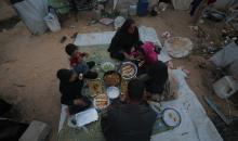 عائلة فلسطينية كفيفة تتناول وجبة الإفطار خارج خيمتها في مخيم بوسط قطاع غزة خلال شهر رمضان