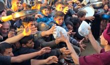 فلسطينيون نازحون يكافحون للحصول على طعام مُتبرع به للإفطار، وجبة كسر الصيام، في اليوم الرابع من شهر رمضان المبارك في مطبخ مجتمعي في خان يونس، قطاع غزة، 21 فبراير/شباط 2026. تصوير: طارق محمد/(APA Images)