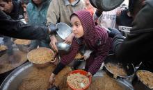تجمع فلسطينيون نازحون، بينهم أطفال ونساء، حاملين أوعية طعام لتلقي وجبات ساخنة وزعتها جمعيات خيرية قبل الإفطار في مدينة غزة في 27 فبراير/شباط 2026.صورة: عمر أشتوي