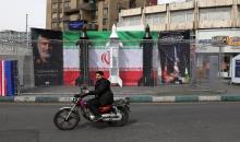 سائق دراجة يمر بجوار نماذج وهمية لصواريخ إيرانية مثبتة على جانب الطريق في طهران في 22 آذار 2026. (أ ف ب).jpeg