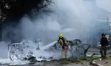 محاولة إخماد حريق اندلع في موقع سقوط شظايا صاروخ إيراني في تل أبيب (غيتي).webp