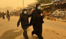 فلسطينيون يسيرون وسط عاصفة رملية في مخيم خيام يؤوي فلسطينيين نزحوا خلال العدوان الإسرائيلي الذي استمر عامين، في خان يونس جنوب قطاع غزة، 14 مارس/آذار 2026. تصوير: طارق محم