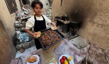ياسر عياد، فتى فلسطيني يبلغ من العمر أربعة عشر عامًا، يمارس مهاراته في الطبخ على نار الحطب بجوار أنقاض منزل عائلته المدمر في مدينة غزة. غزة، 10 أبريل/نيسان 2026. تصوير: محمد الأسود