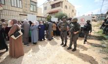 عائلات فلسطينية تنتظر عند نقطة تفتيش تابعة للجيش الإسرائيلي عند مدخل مخيم جنين للاجئين، قرب مدينة جنين في الضفة الغربية، لاستعادة ممتلكاتها من منازلها، 13 أبريل/نيسان 2026. صورة: محمد ناصر