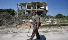 رجل لبناني يمر أمام منزل مدمر في قرية زوطر الغربية جنوبي لبنان، اليوم. (أسوشيتد برس).webp