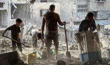 فلسطينيون يتفقدون ما تبقى من ممتلكاتهم وسط أنقاض مبنى سكني استهدفته غارة جوية إسرائيلية في مخيم المغازي للاجئين وسط قطاع غزة، يوم 16 أكتوبر/تشرين الأول 2026. (تصوير: أحمد إبراهيم)