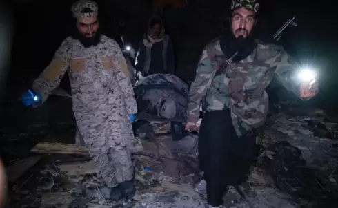 رجال أمن يحملون جثة أحد الضحايا (الفرنسية).webp