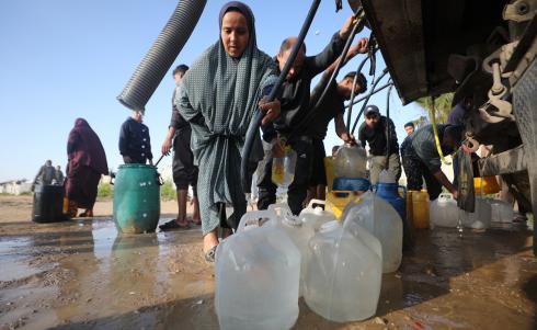 يتجمع الفلسطينيون النازحون لجلب الماء وسط خيام متداعية، ما يعكس تدهور الأوضاع المعيشية والنقص الحاد في الاحتياجات الأساسية، مخيم النصيرات للاجئين وسط قطاع غزة، 31 مارس/آذار 2026. تصوير: حسن الجديدي