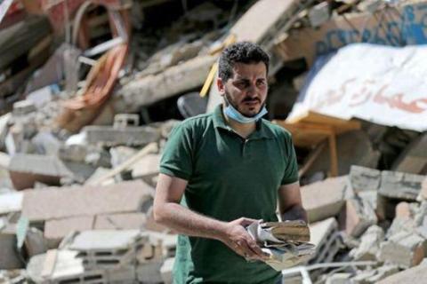  الفلسطيني شعبان اسليم يجمع كتبا من مكتبته التي دُمرت بعد غارة جوية إسرائيلية على غزة في صورة التقطت يوم الاثنين. تصوير: إبراهيم أبو مصطفى - رويترز 