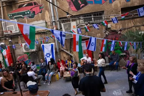 إسرائيليون يرقصون خلال حفل احتفال بالسنة الفارسية الجديدة، المعروف باسم النوروز، في فناء خلفي لمطعم مزين بالأعلام الإسرائيلية والإيرانية، في تل أبيب، AP Photo/Oded Balilty