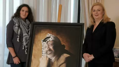 سهى عرفات تقف مع ابنتها زهوة أمام صورة لزوجها الراحل ياسر عرفات في منزلها في مالطا