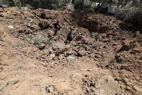 فلسطينيون يتفقدون الأضرار التي لحقت بأرض زراعية بعد أن أصابتها غارات جوية إسرائيلية في بيت حانون شمال قطاع غزة 