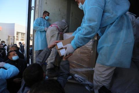 عمال يفرغون حمولة شاحنة من جرعات لقاح Sputnik V في قطاع غزة