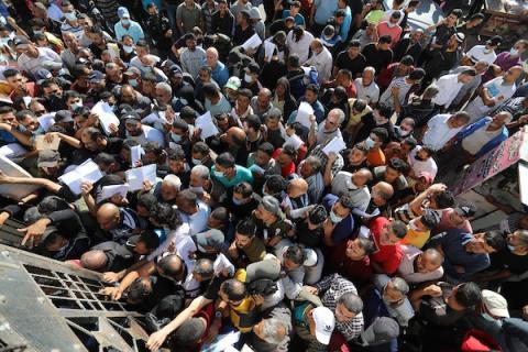 مواطنون فلسطينيون ينتظرون أمام مقر الغرفة التجارية للتسجيل من اجل العمل في إسرائيل، في دير البلح وسط قطاع غزة