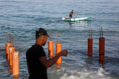 عمال فلسطينيون يديرون جرافة لنصب ركائز في البحر الأبيض المتوسط ​​لبناء مقهى القلعة وهو أول مقهى خرساني عائم على شاطئ مدينة غزة باستخدام مواد بسيطة 4