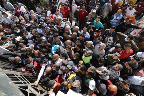     مواطنون فلسطينيون ينتظرون أمام مقر الغرفة التجارية للتسجيل من اجل العمل في إسرائيل، في دير البلح وسط قطاع غزة