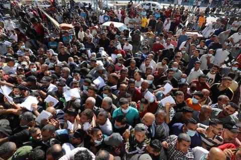  مواطنون فلسطينيون ينتظرون أمام مقر الغرفة التجارية للتسجيل من اجل العمل في إسرائيل، في دير البلح وسط قطاع غزة