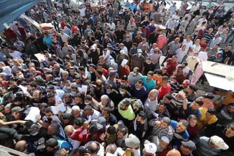 مواطنون فلسطينيون ينتظرون أمام مقر الغرفة التجارية للتسجيل من اجل العمل في إسرائيل، في دير البلح وسط قطاع غزة