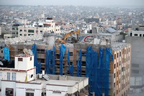    عمال فلسطينيون يعملون على إزالة برج الجوهرة الذي تعرض للقصف الجوي الإسرائيلي خلال التصعيد الأخير في شهر مايو